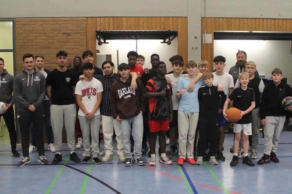 Gruppenfoto von Jugendlichen und Trainern in einer Sporthalle, einige halten B&auml;lle in den H&auml;nden.