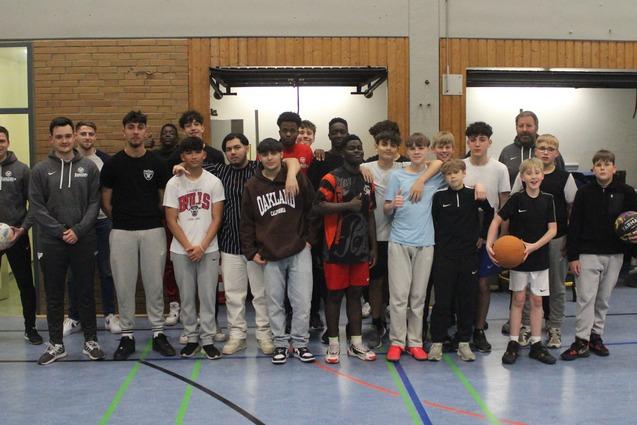 Gruppenfoto von Jugendlichen und Trainern in einer Sporthalle, einige halten B&auml;lle in den H&auml;nden.