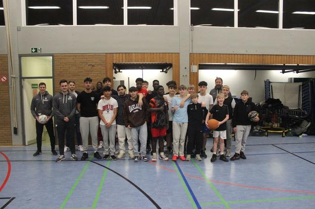Gruppenfoto von Jugendlichen und Trainern in einer Sporthalle, einige halten B&auml;lle in den H&auml;nden.