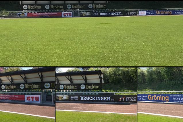 Gr&uuml;n bespielt Fu&szlig;ballfeld mit Sponsorenbannern am Rand, darunter GTU und Bruckinger, teilweise im Schatten.