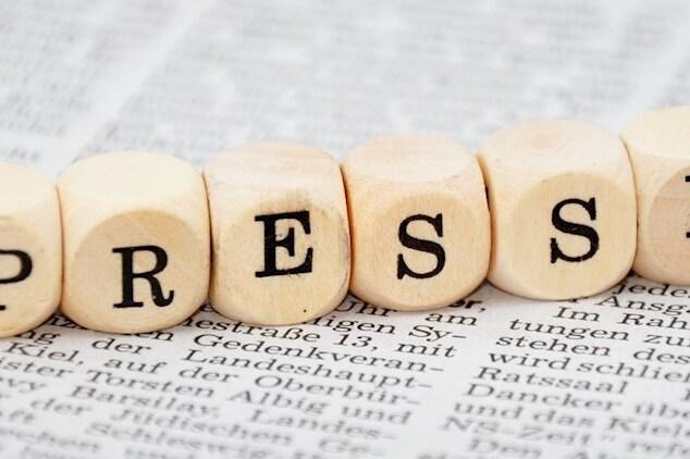 Buchstabenw&uuml;rfel mit der Aufschrift &bdquo;PRESSE&ldquo; auf einer bedruckten Zeitungsseite.