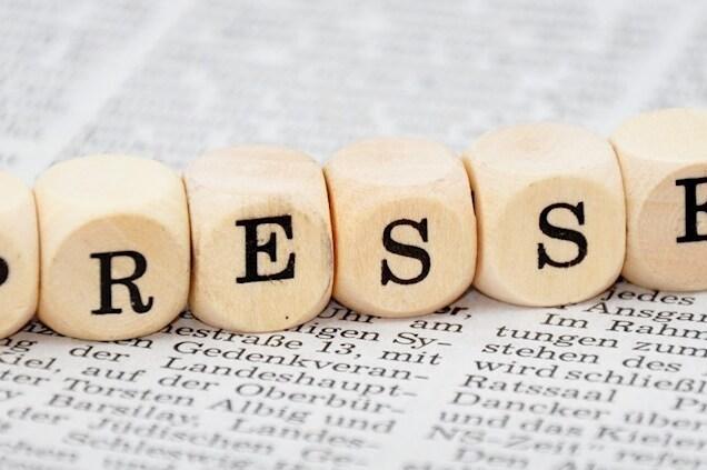 Buchstabenw&uuml;rfel mit der Aufschrift &bdquo;PRESSE&ldquo; auf einer bedruckten Zeitungsseite.